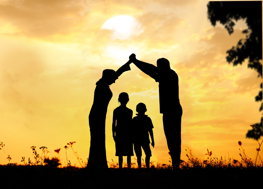 silhouette of a family with two children against a sunset